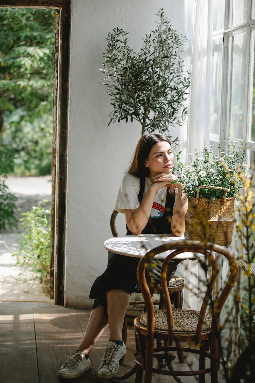 young woman sitting at table with basket of flowers